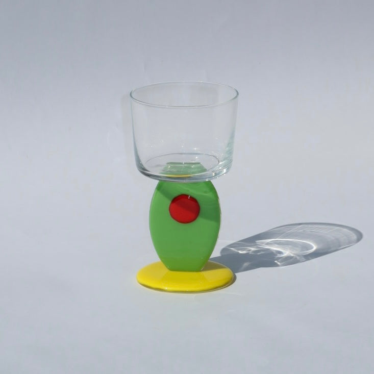 Clear glass with a olive stem on a gray background