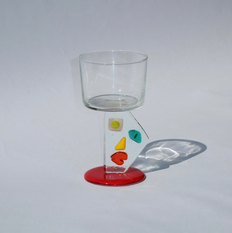 Clear glass with colorful designs on a red base against a gray background