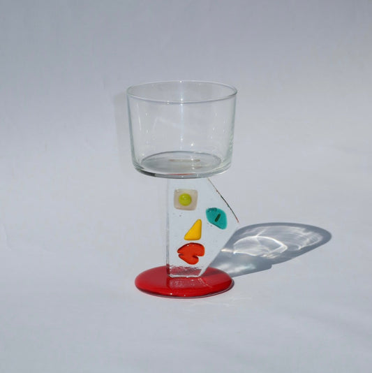 Clear glass with colorful designs on a red base against a gray background