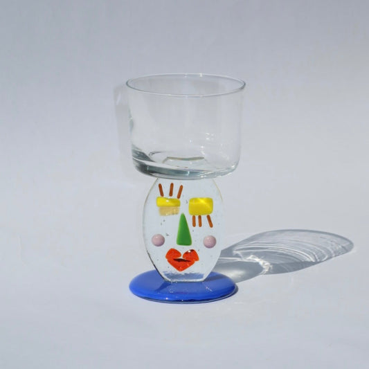 Glass with a colorful face design on a gray background